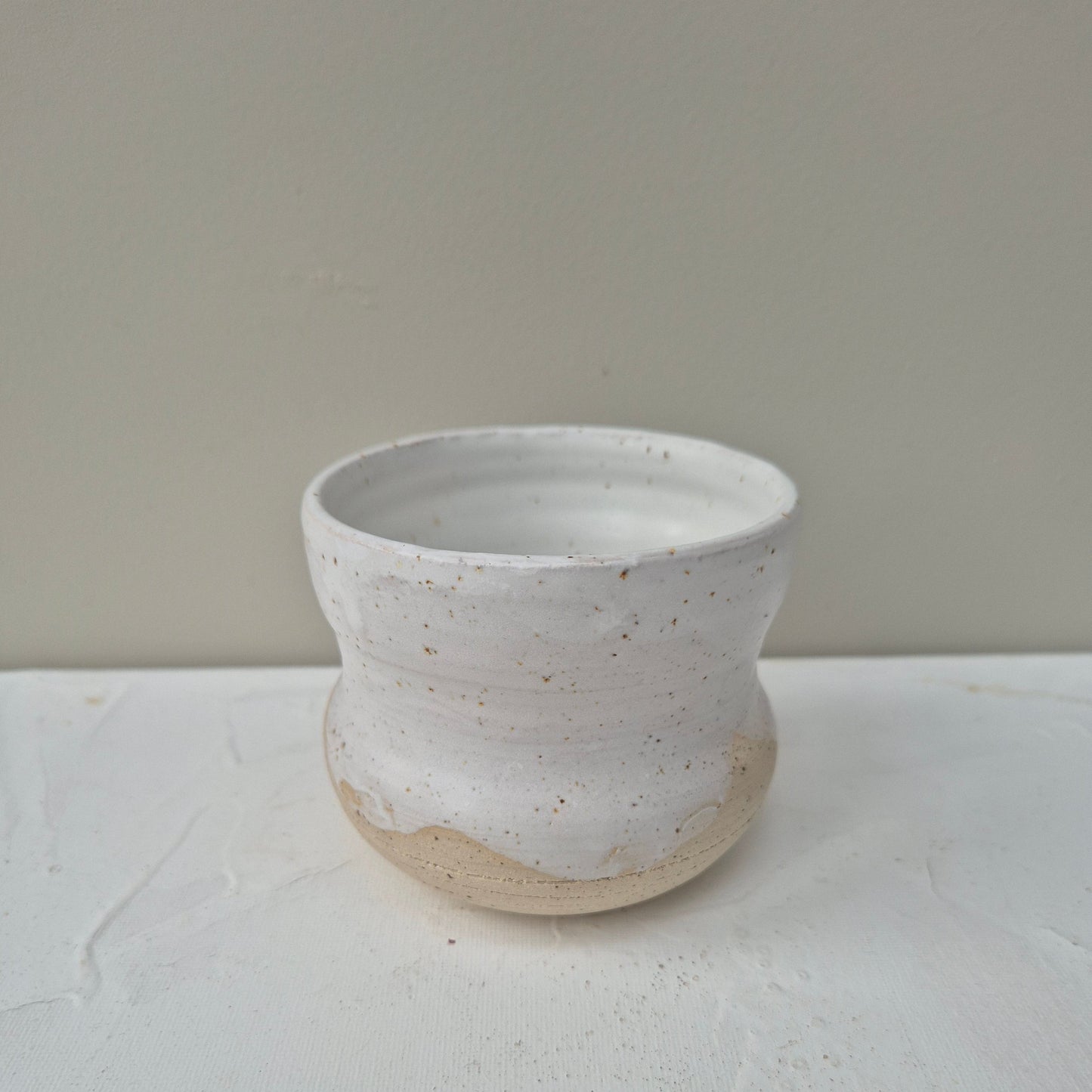 White ceramic vase with a textured surface on a light gray background