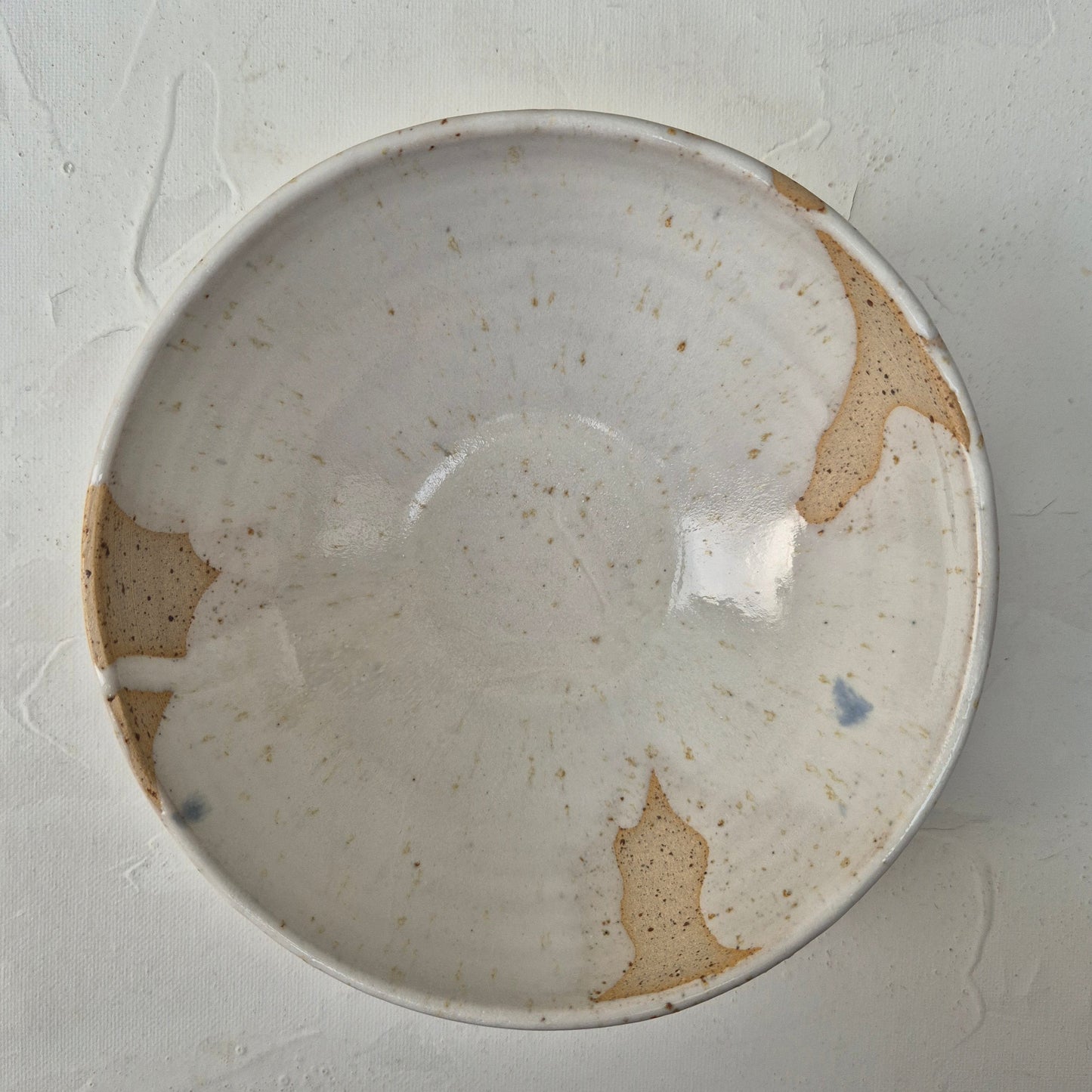 Round ceramic bowl with brown speckles on a gray background