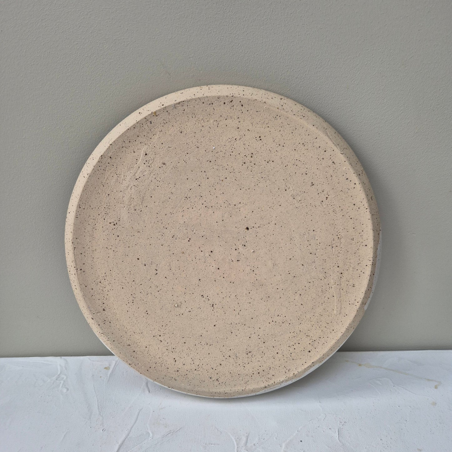  bottom of Round beige ceramic plate on a light gray background
