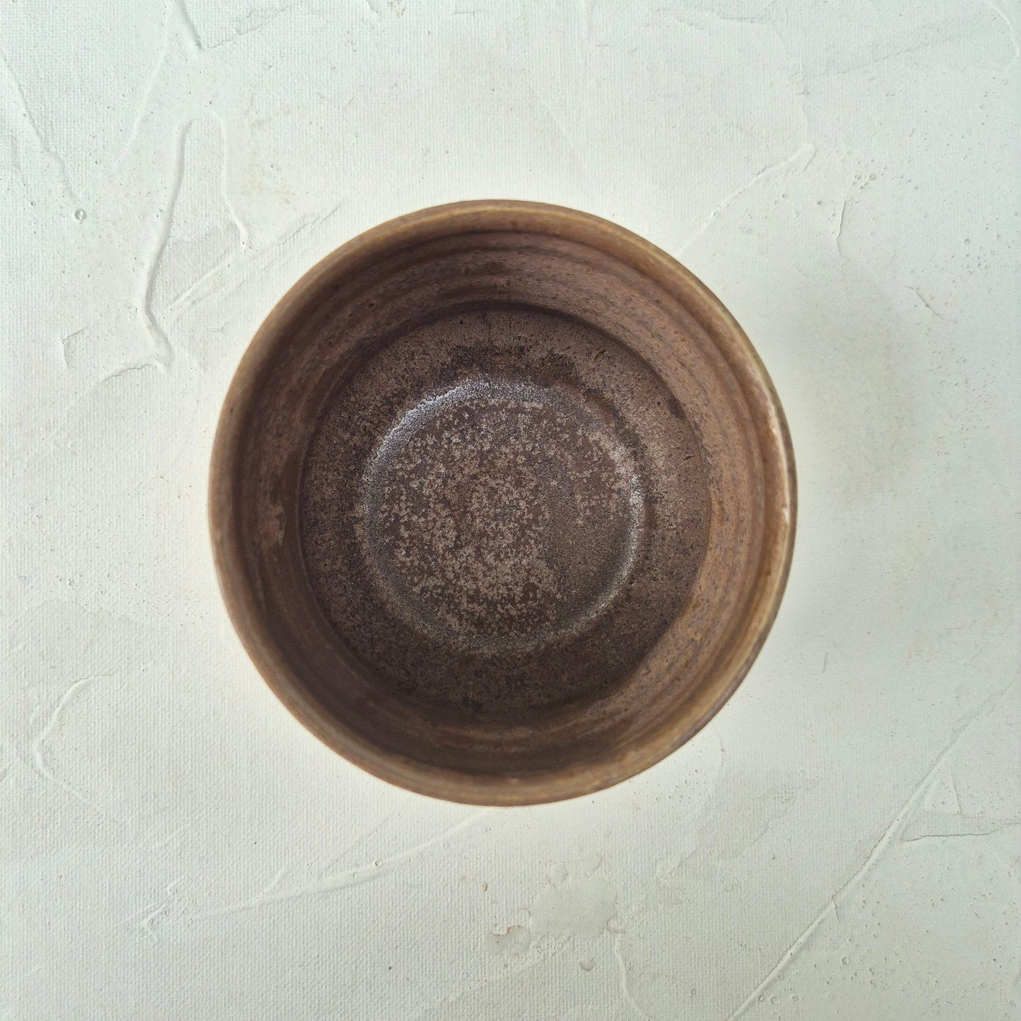 Brown ceramic bowl on a textured white surface