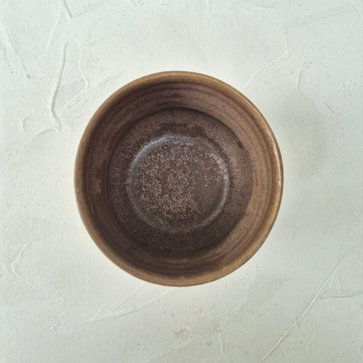 Brown ceramic bowl on a textured white surface