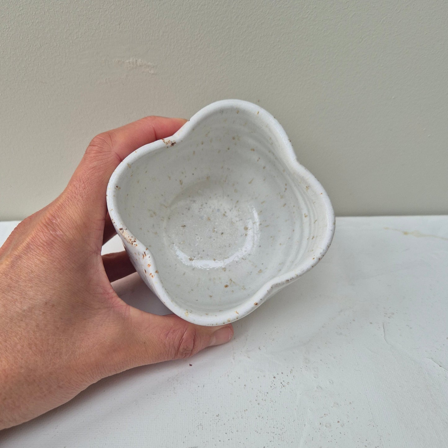 Hand holding a small ceramic bowl against a plain background