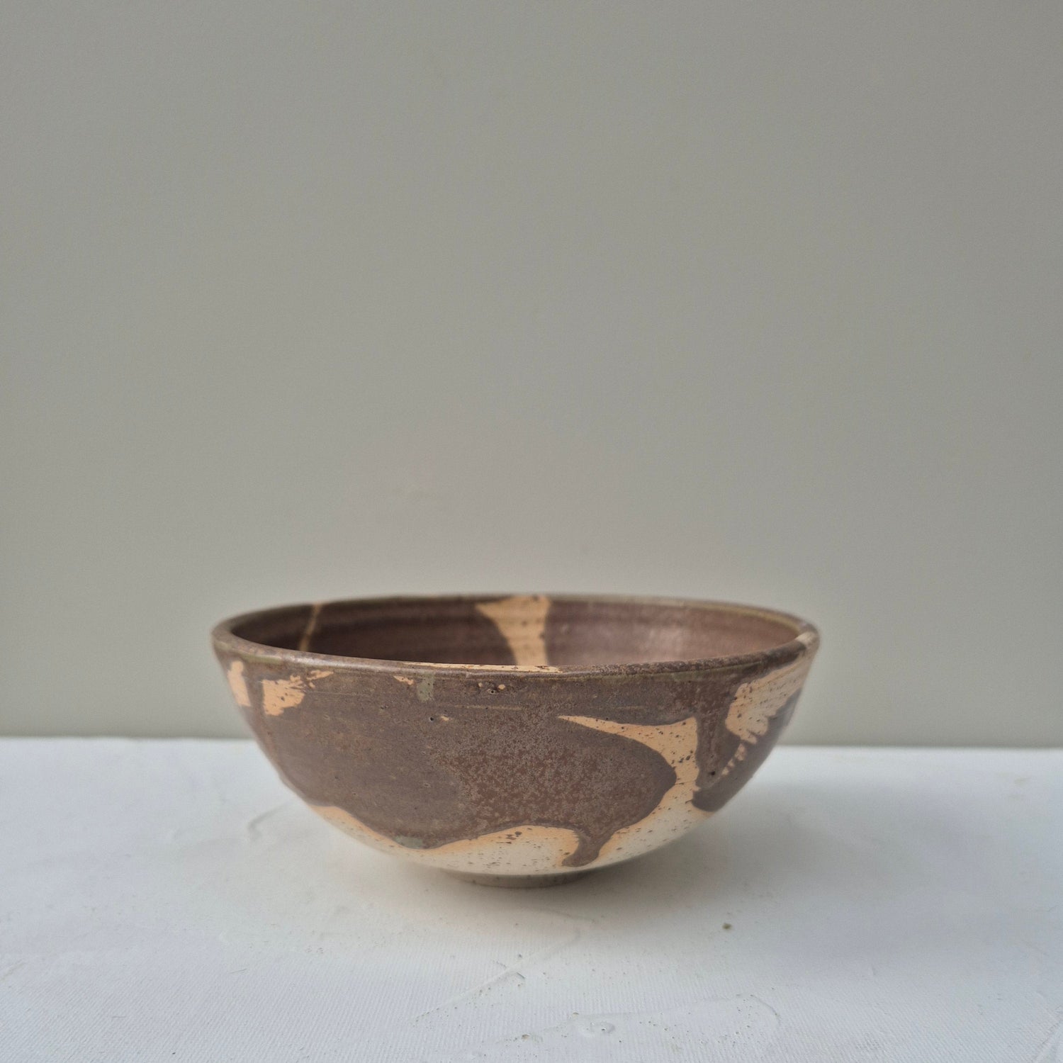 Ceramic bowl with brown and beige pattern on a light gray background