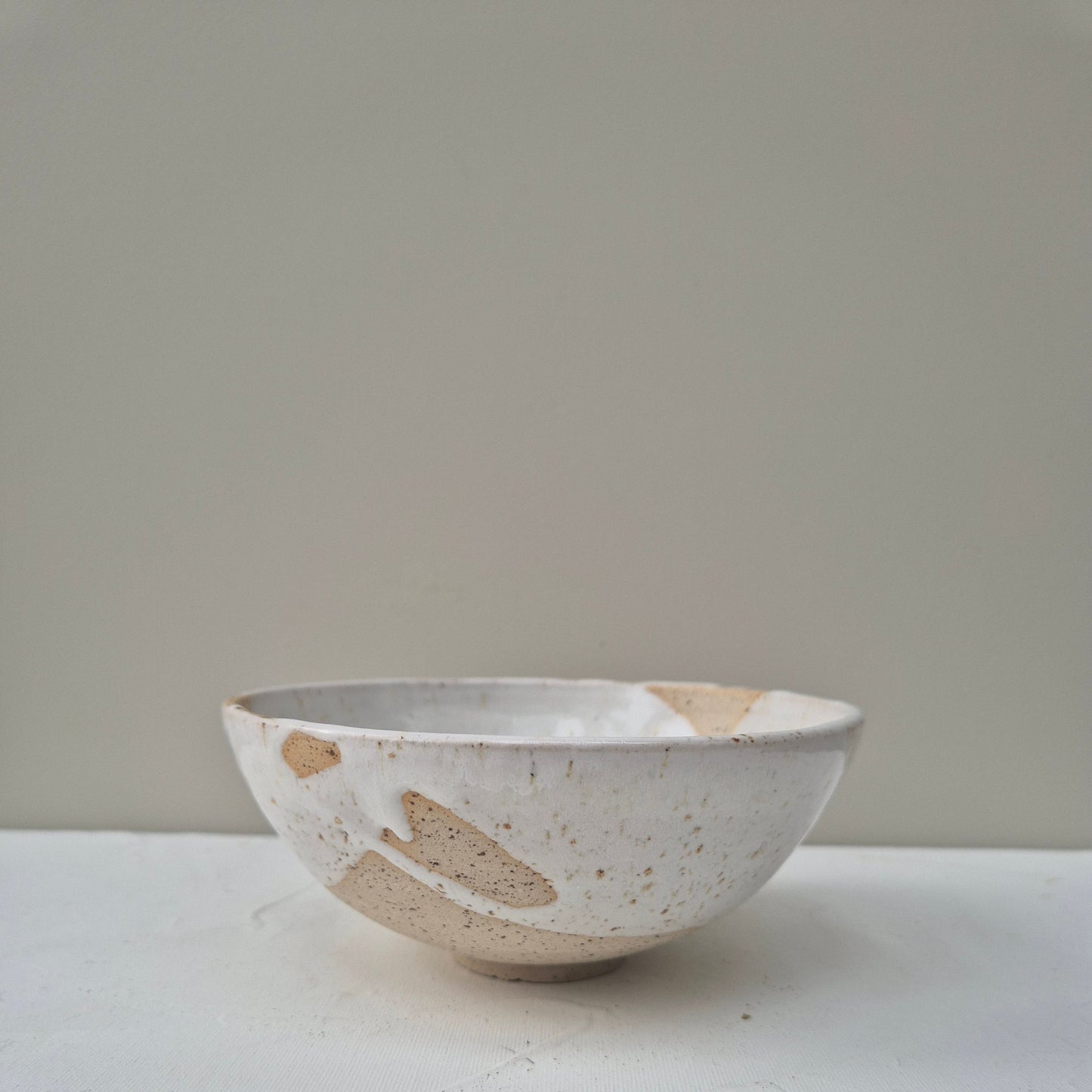 Ceramic bowl with speckled pattern on a plain background