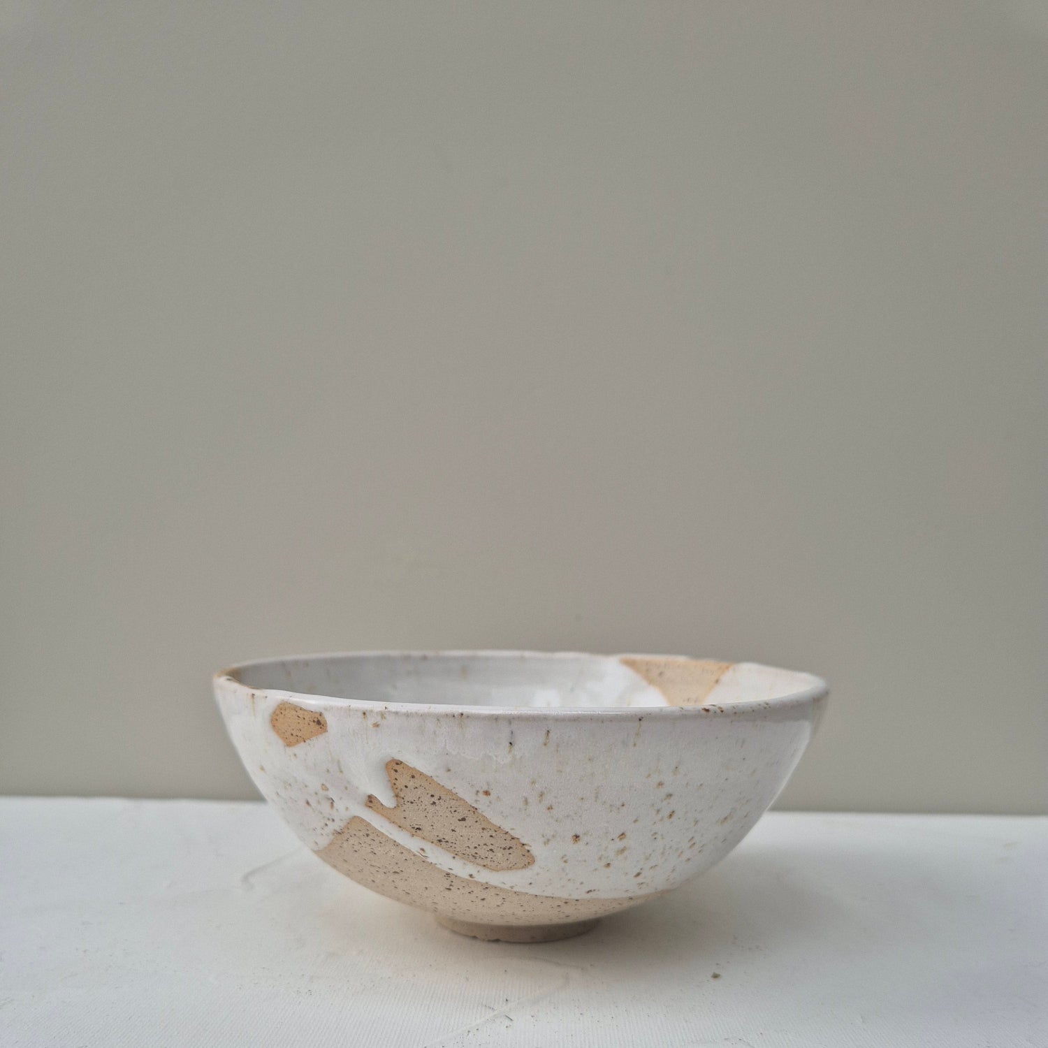 Ceramic bowl with speckled pattern on a plain background