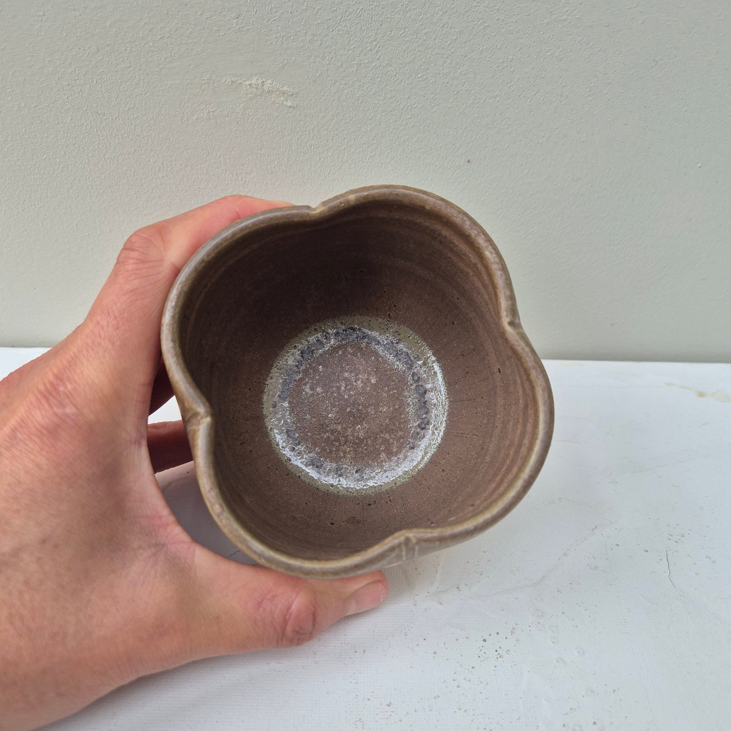 Hand holding a ceramic heart-shaped object against a plain background