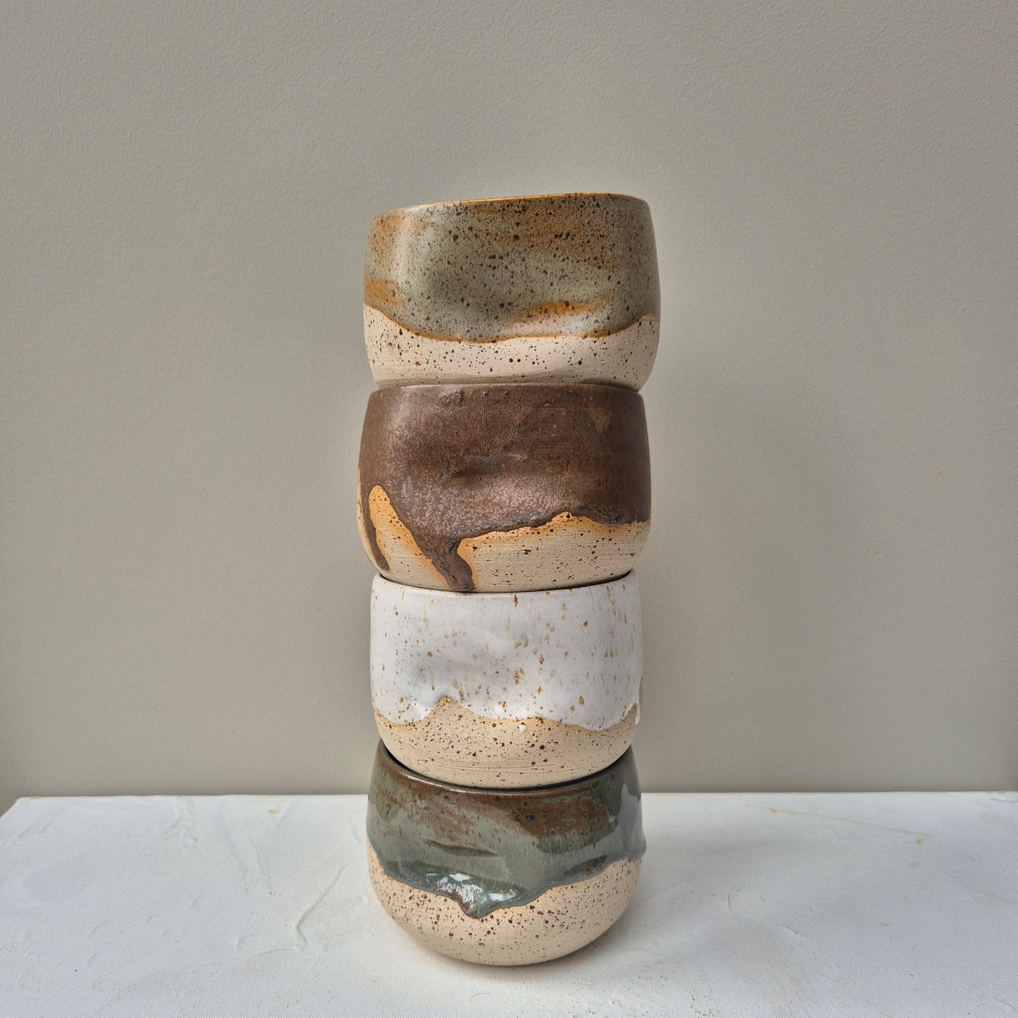 Stack of ceramic pots with layered colors on a neutral background