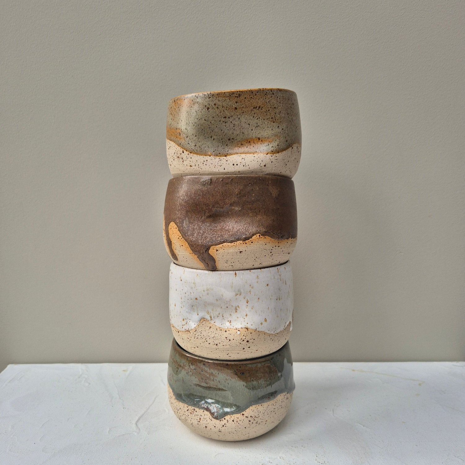 Stack of ceramic pots with layered colors on a neutral background