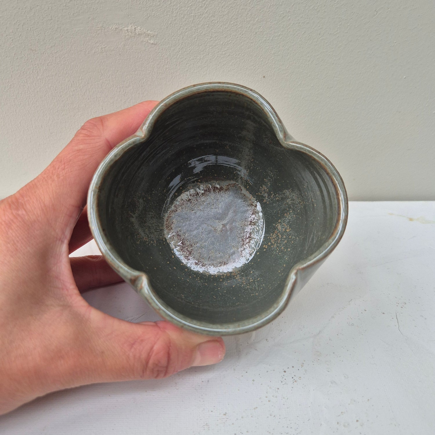 Hand holding a ceramic bowl with a textured surface against a plain background