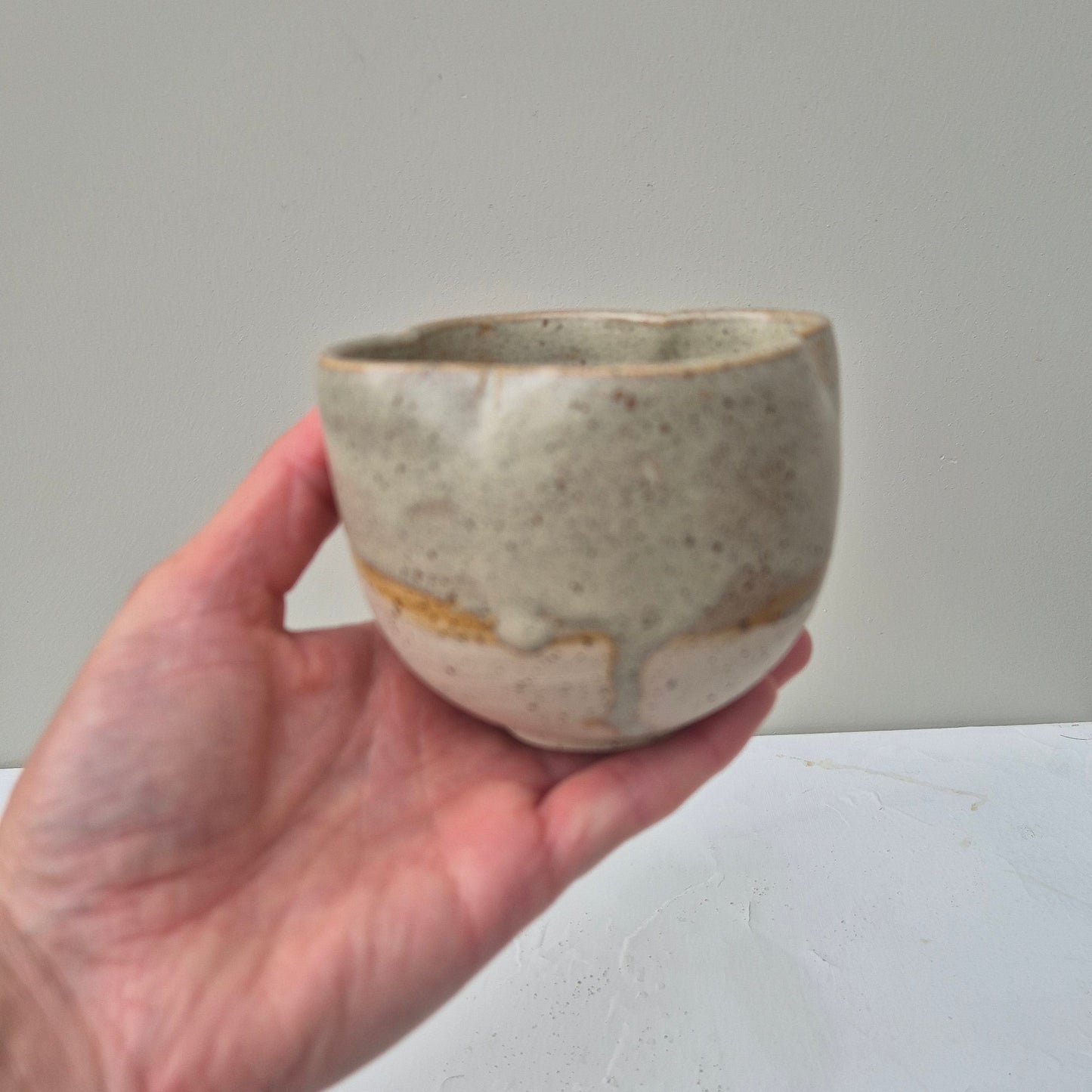 Hand holding a small ceramic bowl against a plain background
